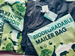 Close-up of biodegradable mailer bags and sustainable shirt promoting eco-friendly packaging. Qu’est-ce que le recyclage textile ? Comment fonctionne le recyclage textile ?